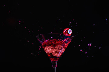Casino dice falling into glass of alcohol drink on black background