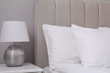 White soft pillows on bed and lamp in room