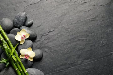 Fototapeten Spa-Steine, schöne Orchideenblüten und Bambusstiele auf schwarzem Tisch, flach gelegt. Platz für Text © New Africa