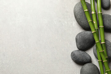 Fototapeta na wymiar Spa stones and bamboo stems on light grey table, flat lay. Space for text