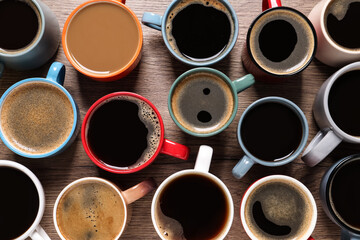 Cups of hot coffee on wooden table, flat lay