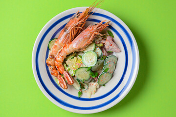 A healthy green garden salad with cooked shrimps over green background. Delicious dinner idea, healthy food.