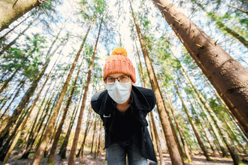 portrait of attractive nerd in long sleeve black coat and orange hat with glasses and protective...