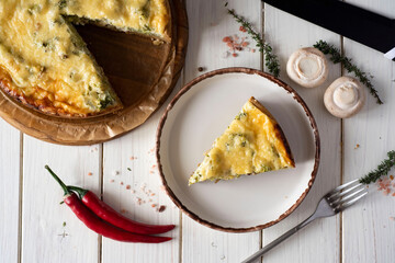 A slice of Lauren's quiche on a white plate on a white table. A piece of meat pie on a nice plate. Top view.