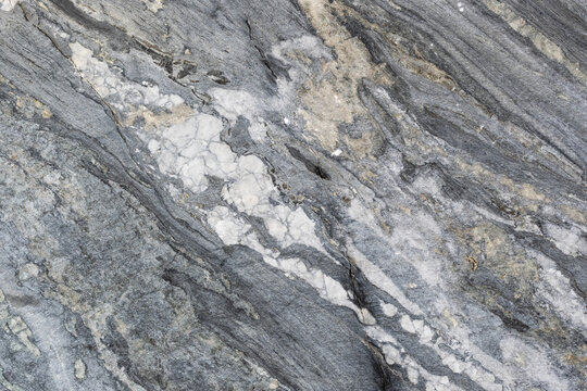 Slab of natural gray untreated marble. Korela marble interspersed with beige, white, greenish-gray shades. Natural finishing stone with a beautiful pattern and cracks.