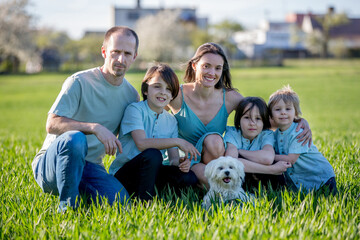 Beautiful family with kids, mom, dad, three boys and a dog, playing in the park