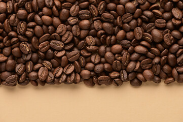 Roasted coffee beans on beige background with copy space. Close up top view.