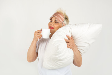 beautiful adult woman aged with a pillow and a cup of tea on a white background 