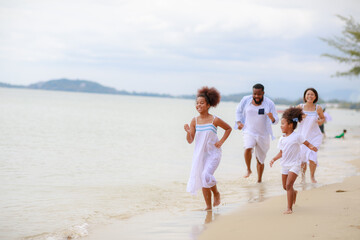 Happy African family walking relax on the beach with 2 daughters.