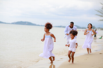 Happy African family walking relax on the beach with 2 daughters.