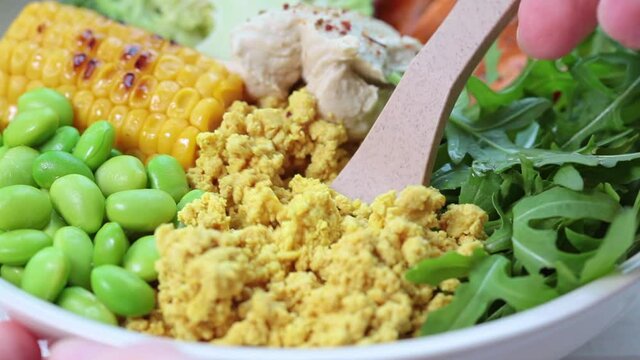 Vegan breakfast bowl - scrambled tofu, corn, beans, sweet potato and broccoli. Plant-based diet concept.