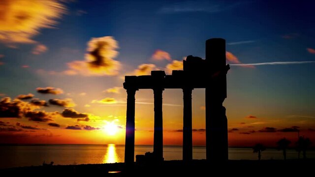 Columns of ancient Greek ruins against the backdrop of sunset. Sunset timelapse with orange sky. time lapse