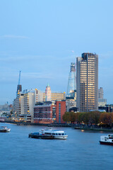 Fototapeta premium Vertical crop portrait of the River Thames in London at evening showing boats in the foreground and the oxo building and partially built shard 