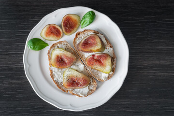 Bruschettas with figs and gorgonzola on white plate, closeup