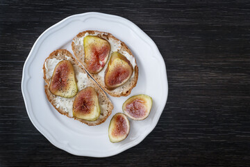 Fototapeta na wymiar Bruschettas with figs and gorgonzola on white plate, closeup