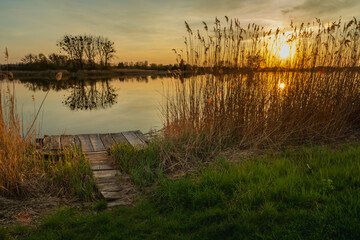 Wooden platform by the lake shore and sunset