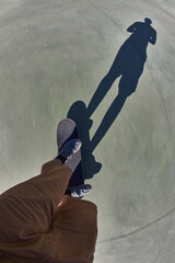 Unrecognizable skateboarder feet with his shadow silhouette on a motion blur ground