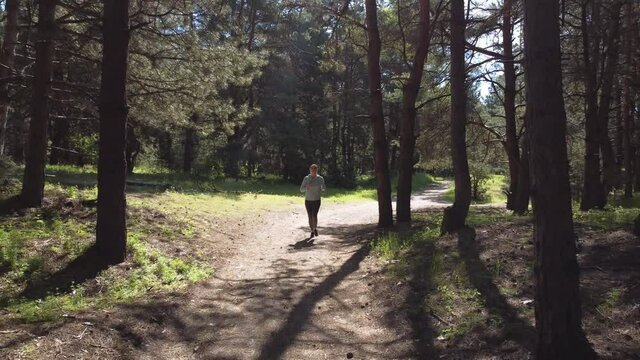 Young Woman Running on the Forest Trail at Warm Spring Morning. Sport and Active Lifestyle.