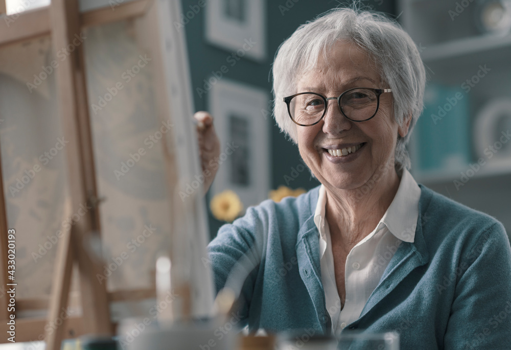 Wall mural Happy elderly woman painting at home