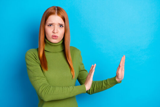 Photo of unhappy disgusted young woman hold hands empty space prohibition isolated on blue color background