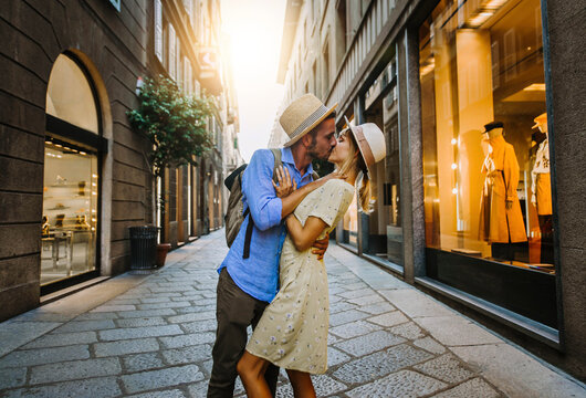 Couple of lovers kissing on city street at sunset - Two tourists having fun walking in town - People, love and tourism concept