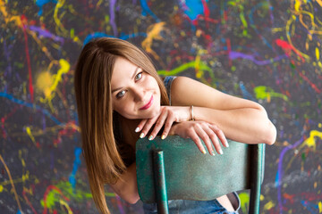 Portrait of a beautiful woman with dark hair, clean  skin and natural makeup. Natural, beautiful smile. Woman is wearing a denim overalls.
Used background using oil paints.