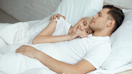 Fototapeta na wymiar cheerful blonde woman resting in bed with boyfriend