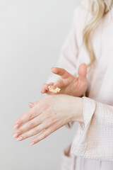 beautiful female hands smear cream close-up on a white background