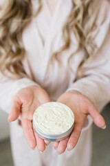 Fototapeta premium a girl with long hair and in a dressing gown holds a cream in her hands
