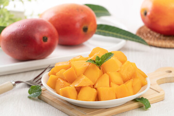 Diced fresh mango fruit on a white plate with leaves.
