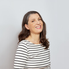 Cover picture portrait of a laughing middle aged woman with beautiful long brown hair, neutral background.