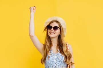 Obraz na płótnie Canvas Happy young woman in sunglasses and summer hat celebrating victory over yellow background, victory, delight concept
