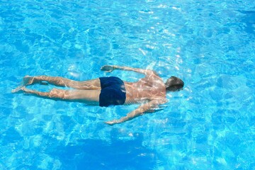 Young athletic man swimming in the swimming pool. Active sport