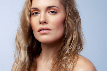 Obraz premium Beautiful blonde with wavy hair close up. Skin care, nude makeup