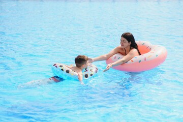 Happy child and woman playing in swimming pool. Summer vacation concept