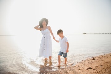 Mother and son playing on the beach at the day time. Concept of friendly family.