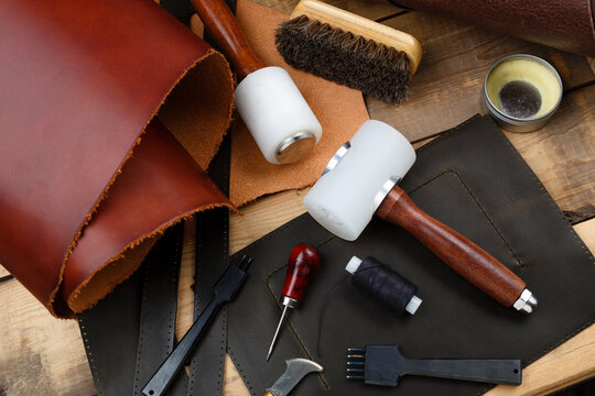 Leatherworker's tools on a wooden workbench.