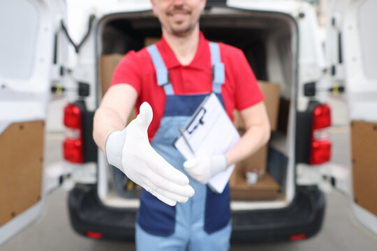 Male courier with documents giving his hand to client for handshake closeup