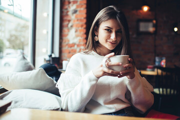 Optimistic woman drinking coffee while resting