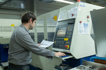 Fototapeta na wymiar Arbeitsvorbereiter kontrolliert Laseranlage in Metallbau-Firma