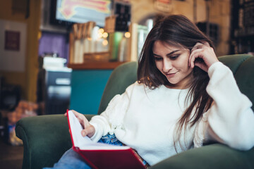 Satisfied woman reading notebook while studying