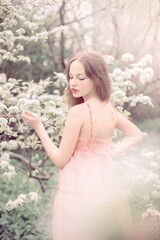 Fototapeta na wymiar Portrait of a beautiful girl near a blossoming tree