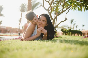 Fototapeta premium happy young mother with son lying on grass