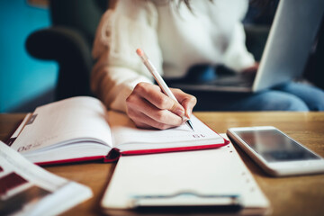 Crop woman taking notes in notepad