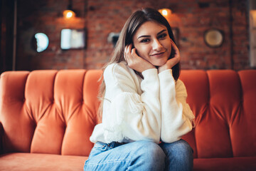 Obraz premium Positive woman on sofa leaning on hands
