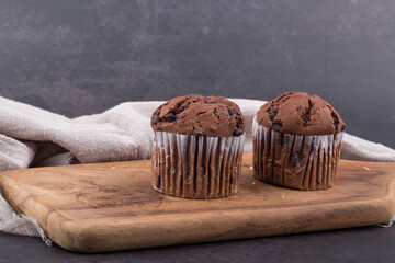 Chocolate dark muffins on wooden plate close up.