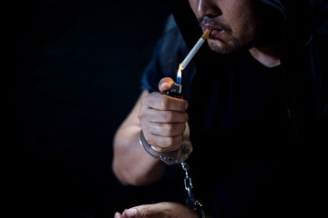 Fototapeta na wymiar Young man of prisoner in handcuffs smoking a cigarette