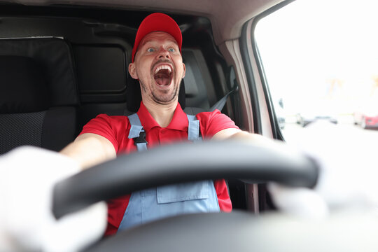 Happy male courier riding behind wheel of car with open mouth