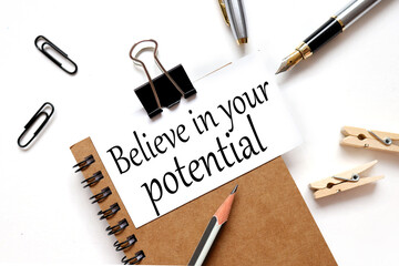 Believe In Your Potential. Motivational quote. the inscription on the business card is attached to the notebook.