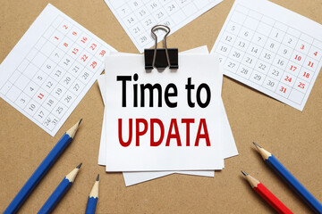 Time to Update.the text on the sticker near the calendar and karagdash. the paper is clamped with a clerical clip. paper on wood background